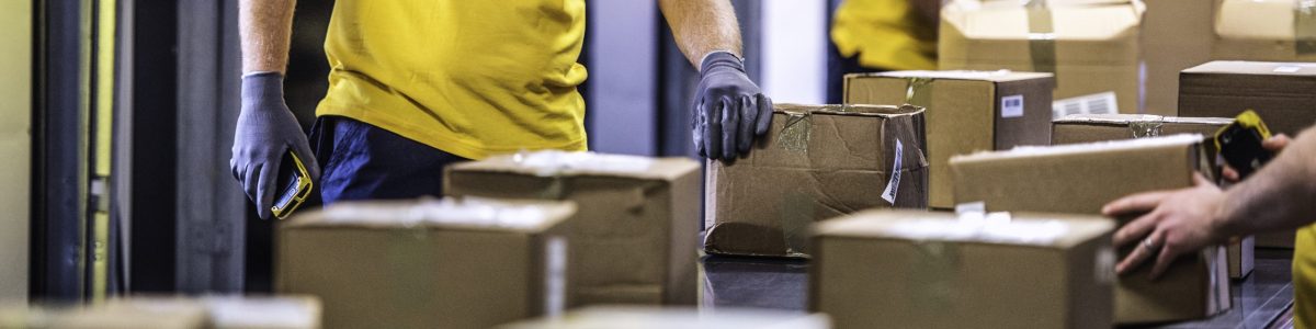 Unrecognisable delivery warehouse workers handling packages on conveyor belt.