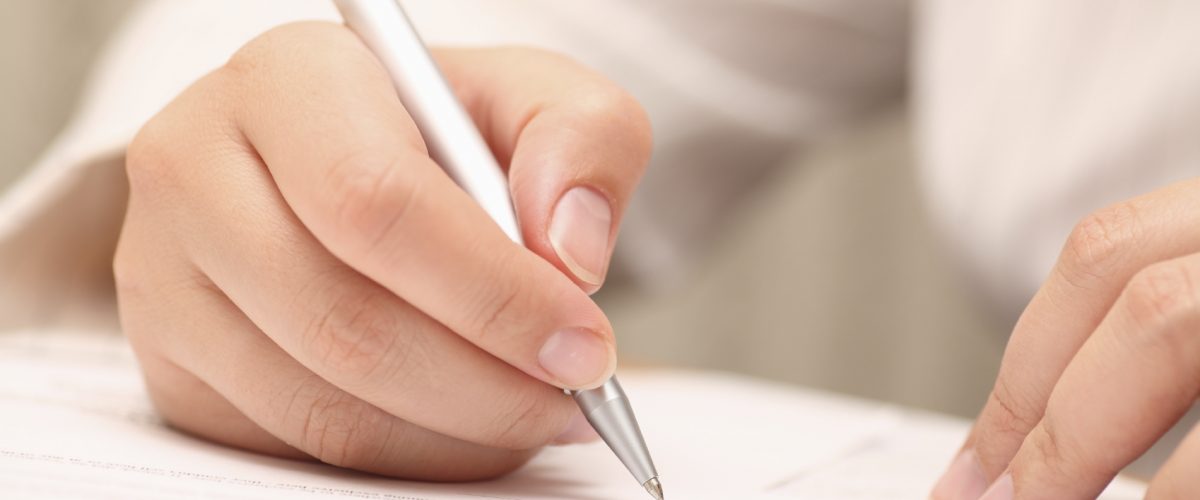 Businesswoman viewing the contract before signing. Close-up. Focus on pen. Shallow depth of field. EOS 5D