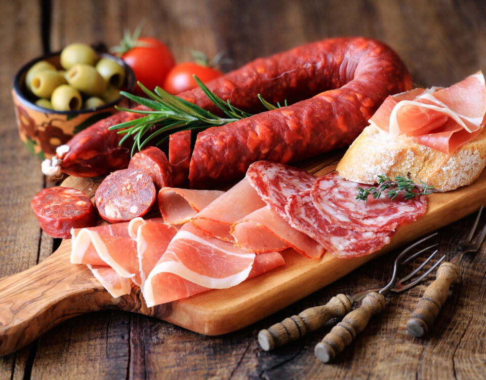 Cured meat platter of traditional Spanish tapas - chorizo, salsichon, jamon serrano, lomo - erved on wooden board with olives and bread